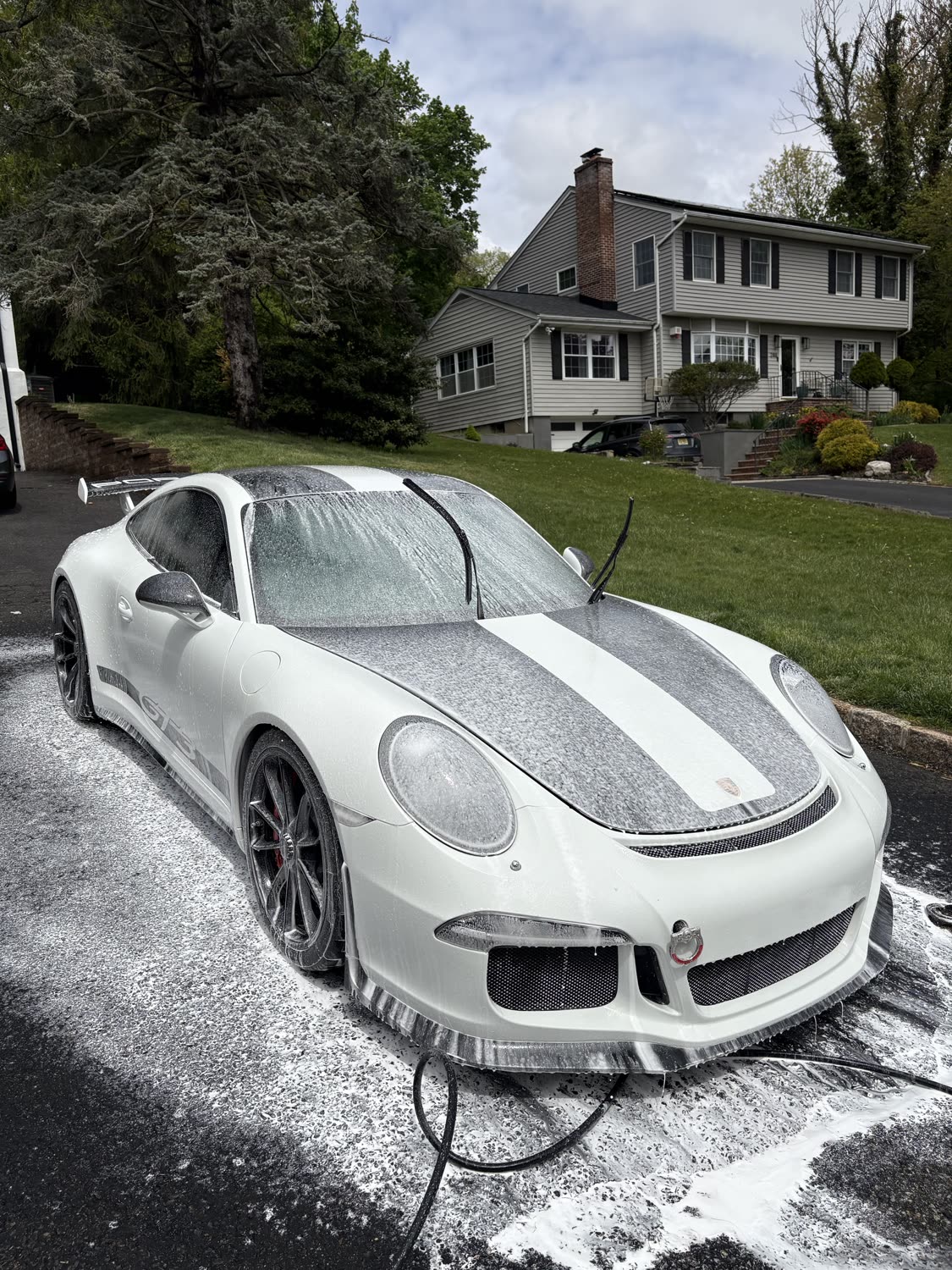 White Porsche 911 covered in cleaning foam during an exterior wash